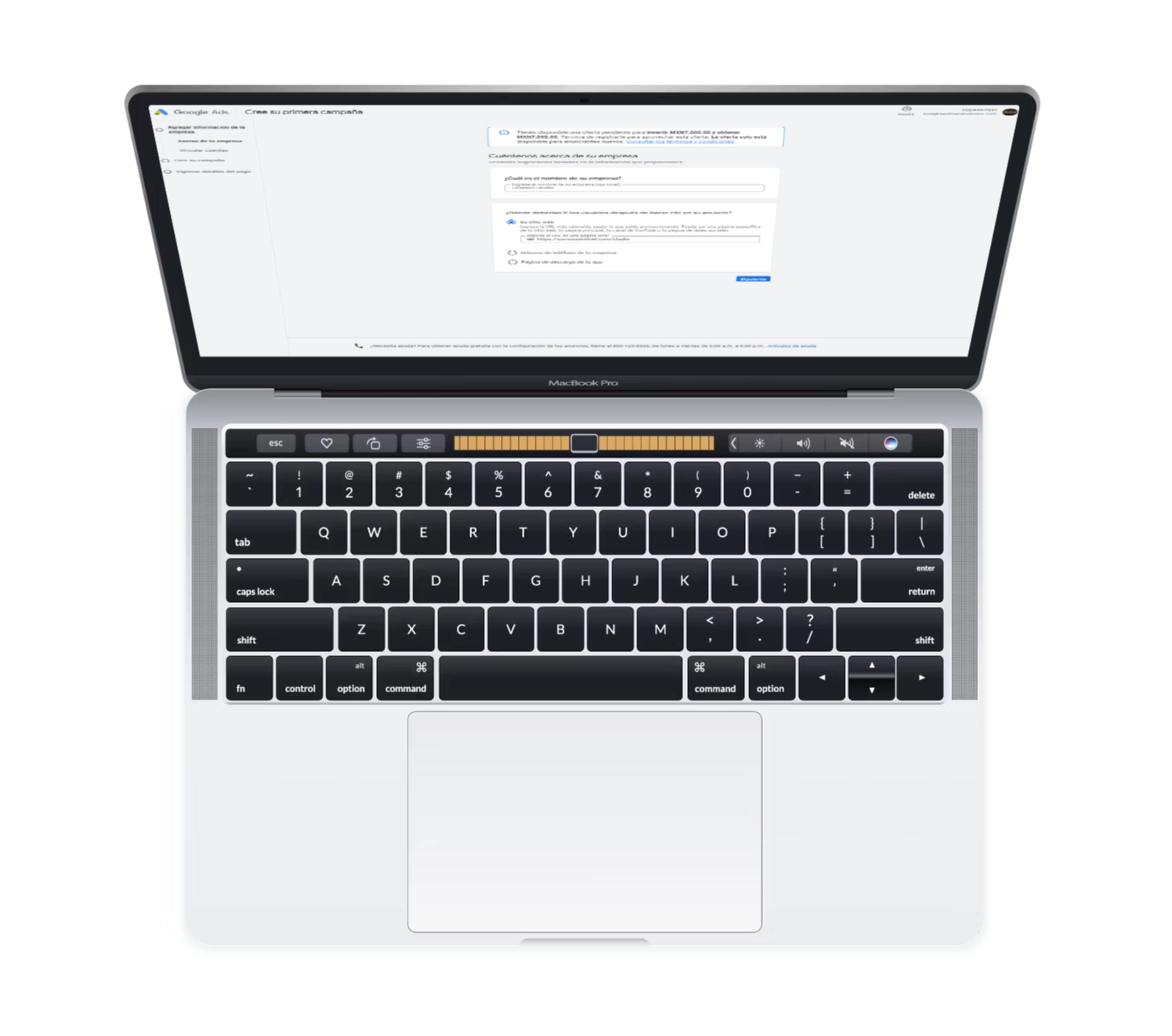 Un portátil MacBook Pro plateado visto desde arriba con la pantalla abierta, mostrando una interfaz basada en texto para la gestión de campañas publicitarias en redes sociales. El teclado negro tiene una barra táctil y el trackpad está centrado debajo.